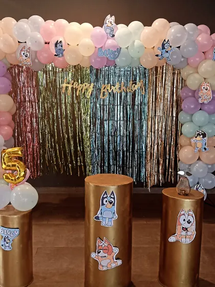 This is the main backdrop for the Bluey-themed party, combining a pastel balloon garland with a multi-colored fringe curtain. The setup is perfect for photos and serves as the central point of the celebration.