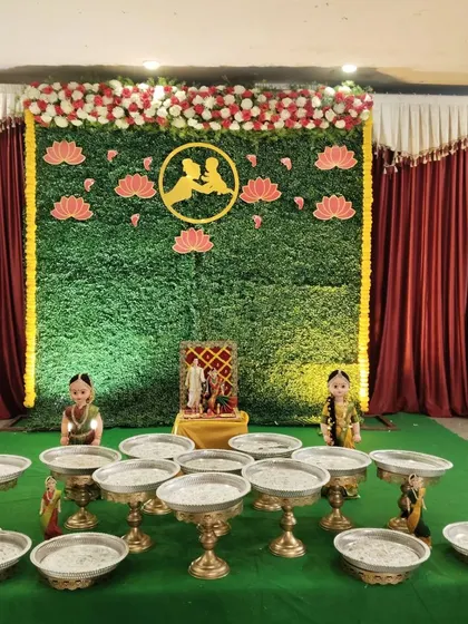 A full view of the elegant artificial flower setup with plate decor. The green backdrop makes the pink lotus cutouts and floral arrangements pop.