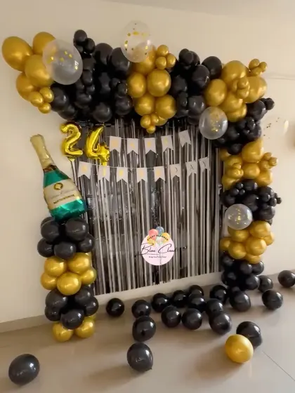 A sophisticated black and gold balloon arch with a shimmer curtain for a 24th birthday celebration.