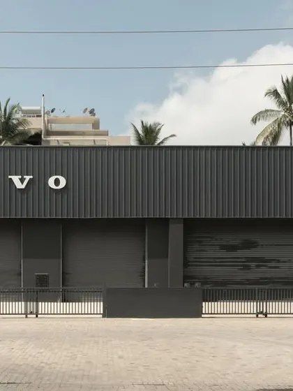 The front facade of the Volvo Vehicle Tech Lab. The dark, corrugated metal panels and clean typography create a strong brand presence, while the large roller doors provide the necessary functionality for a vehicle testing facility.