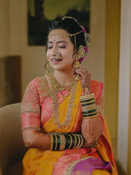 A beautiful, smiling portrait of the bride, capturing the intricate details of her jewelry and henna.