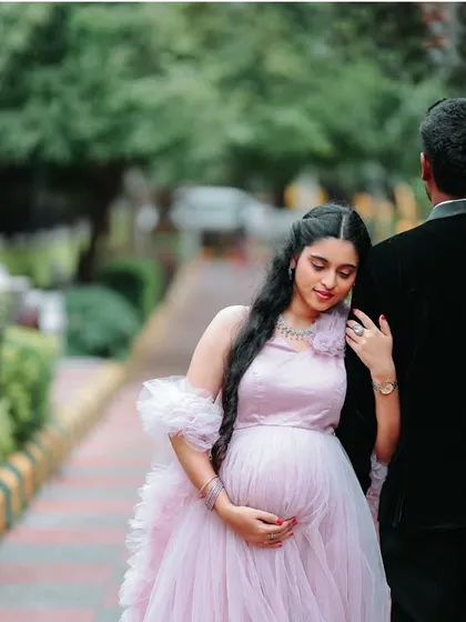 A quiet, intimate moment captured from behind. This angle showcases the fit of the gown and the tender connection between the couple as they await their baby.