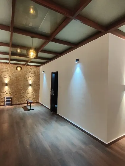 Another angle of the sunroom, showing the combination of a brick accent wall and clean white walls. The strategic use of uplights and downlights creates a warm and inviting ambiance in the evening.