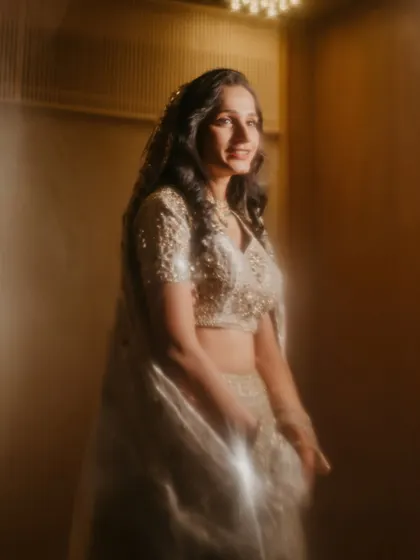 A dreamy and ethereal portrait of the bride, Sanjana. The soft, glowing filter adds a magical quality to her elegant ivory lehenga.