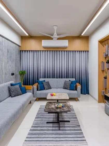 A contemporary living room with grey sofas and a wooden TV unit that also functions as a partition. This is a smart way to define spaces in an open-plan home.