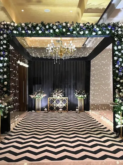 A close-up of the chic black and white entrance for a Sangeet night. The floral arch is made of blue and white flowers, perfectly complementing the modern and graphic look of the chevron walkway.