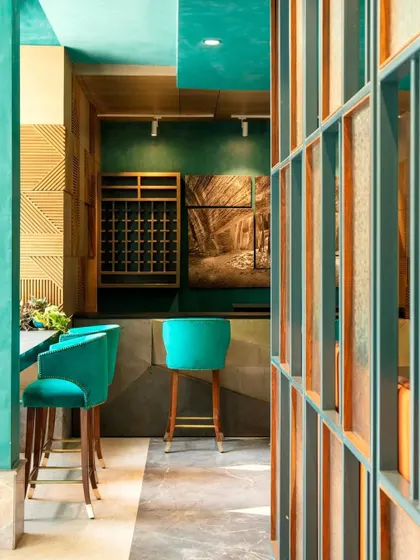 A view into the bar area at The Restaurant at Hibiscus. The design uses a rich color palette and a play of textures, from lime-washed walls to a cubism-inspired brass bar, to create a feast for the eyes.