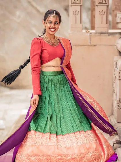 A playful, twirling shot that shows the beautiful movement and flow of the pleated green skirt.
