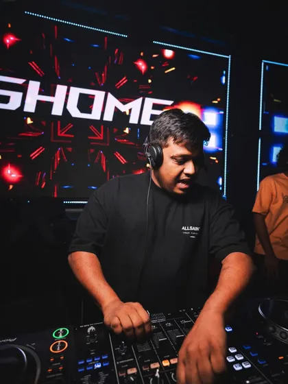 A close-up of me at the decks, with my name in lights behind me. This shot captures the concentration it takes to manage a high-energy set.