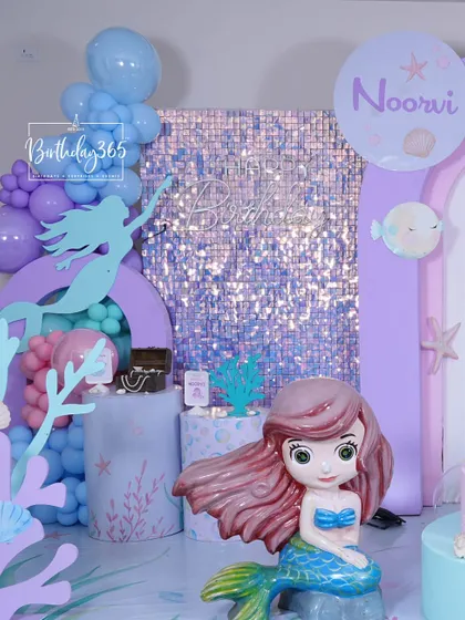 A close-up of the Little Mermaid party for Noorvi, featuring a large Ariel prop and a shimmering sequin backdrop.