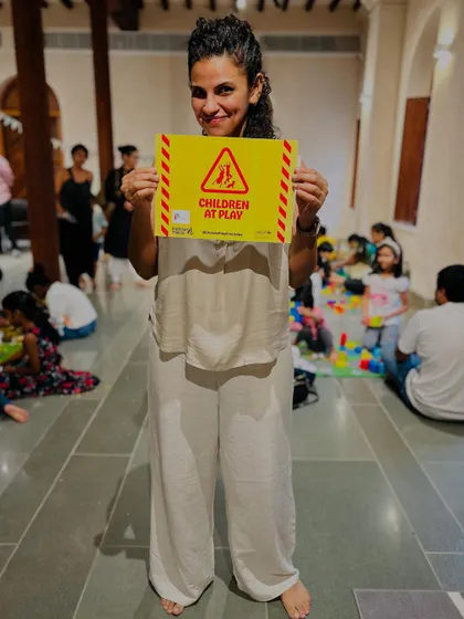 A parent proudly holds a "Children at Play" sign, joining our advocacy campaign to protect every child's right to play.
