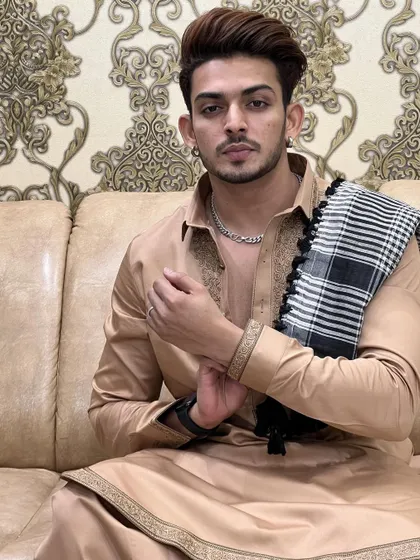 A relaxed moment in a custom-made beige Pathani suit. The fine embroidery and comfortable fit make it an ideal choice for festive gatherings at home.