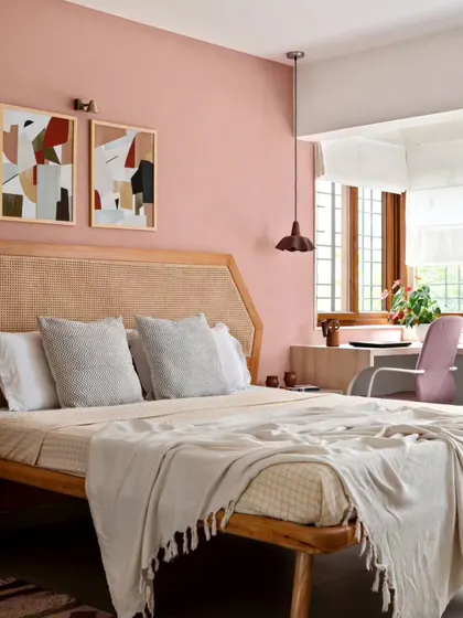 An earthy peach wall, geometric art, and a terracotta pendant lamp create a soothing synthesis in this Japandi-style bedroom. The custom rattan headboard adds a layer of natural texture, contributing to the room's warm and harmonious feel.