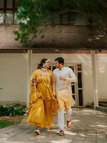 A full-length shot of the couple during their Haldi event, showcasing their coordinated yellow outfits and the relaxed, happy vibe of the day.