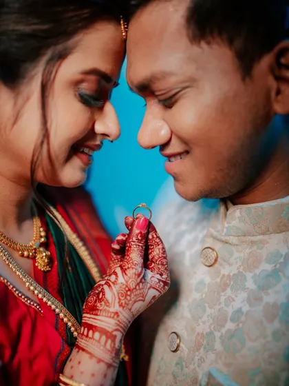 A close-up shot focusing on the engagement ring, with the couple sharing a moment in the background.