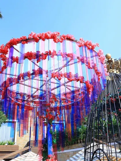 A unique hanging installation made of colorful acrylic strips and flowers. This modern chandelier adds a pop of color and a touch of whimsy to the outdoor Haldi setup.