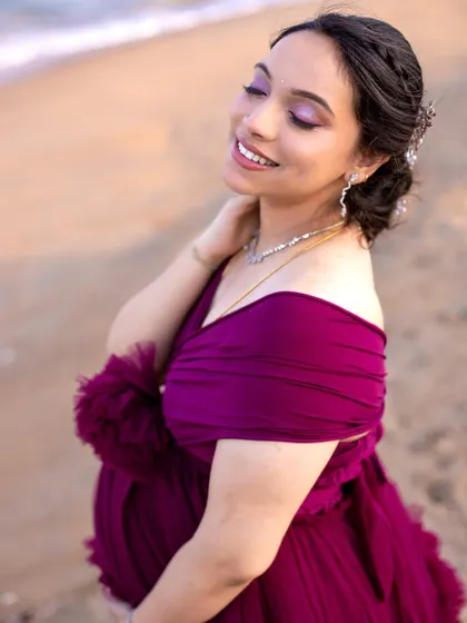 The soft smile and gentle touch on the belly capture a perfect moment of maternal bliss during this beach photoshoot.