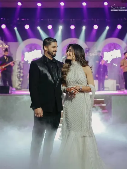 The couple shares a look of love on the smoke-filled stage, with the live band in the background. A perfect candid moment from their reception night.