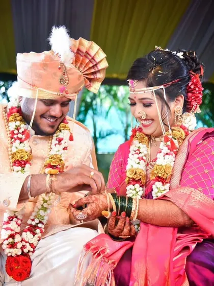A happy moment during the ring exchange ceremony, with the couple dressed in beautiful pink and purple traditional wedding attire.