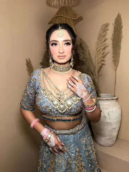 The full look, showing the beautiful contrast between the blue lehenga, gold embroidery, and pink bangles.
