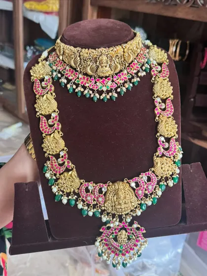 A beautiful temple jewellery set on display. The choker and long haram both feature intricate goddess motifs and are studded with kemp stones.