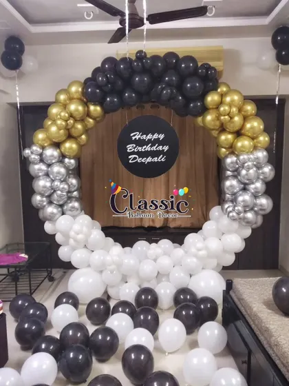 A modern and chic balloon ring in black, white, silver, and gold, with a personalized center plate, perfect for a stylish home party.