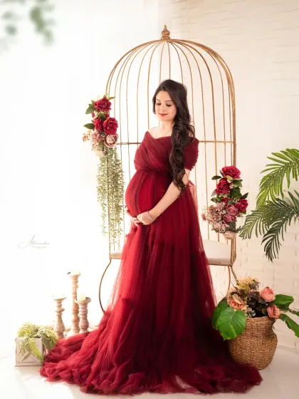 Our studio is filled with beautiful props, like this golden birdcage and floral arrangements, which add a touch of whimsy to this portrait in a deep red gown.