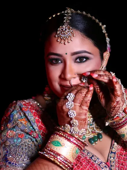 The bride adjusts her nose ring, her hands beautifully decorated with henna and jewelry, a perfect capture of bridal details.