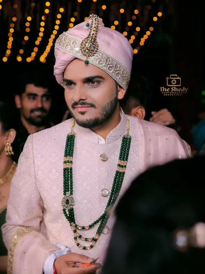 A portrait of a groom looking sharp in a pink sherwani and a green beaded necklace. We capture the unique style and colour combinations of each wedding.