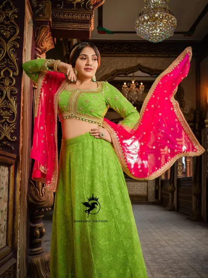 A stunning studio shot of the lime green and pink lehenga worn by Nishvika. The flying dupatta adds a touch of drama and showcases the beautiful bandhani print.