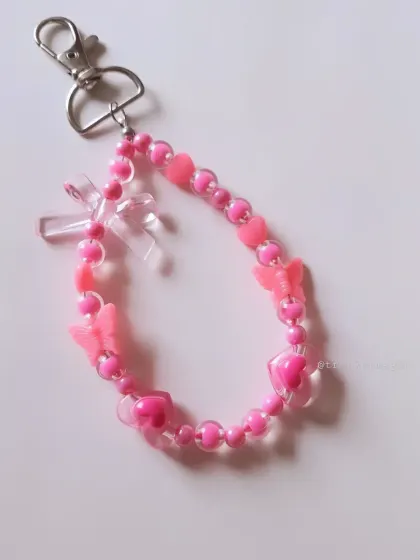 A super cute pink beaded bag charm, adorned with hearts and butterflies. This is the ultimate accessory for anyone who loves all things pink and girly.