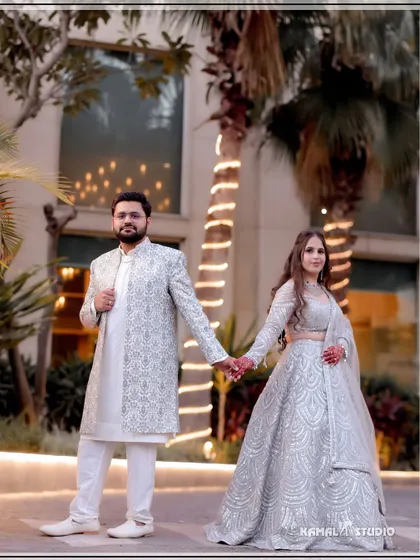 A classic couple portrait, holding hands against a modern architectural backdrop, showcasing their elegant attire.