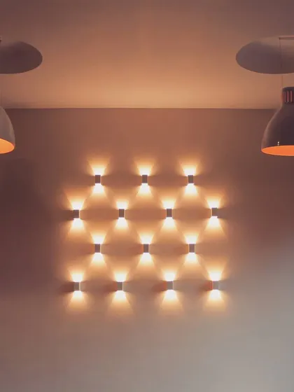 A feature wall of lights at the Priyadarshini Hotel. This symmetrical arrangement of up-and-down lighters creates a captivating diamond pattern of light, transforming a simple wall into a dynamic visual element.
