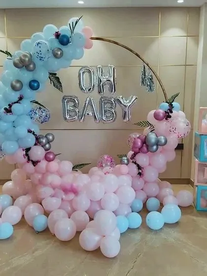 An "Oh Baby" gender reveal or baby shower setup with a half-and-half pink and blue balloon crescent on a ring frame.