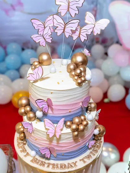 A stunning multi-layered cake decorated with butterflies and gold accents for a first birthday. Our photography highlights the craftsmanship of your event vendors.