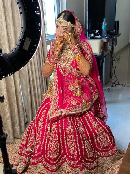 A behind-the-scenes shot of my stunning Marwadi bride getting her final touches. Her red lehenga and heavy jewellery are paired with a classic makeup look.