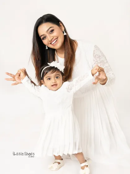 A playful and interactive moment between a mother and her daughter. Their happy expressions and matching outfits make this a delightful photo.