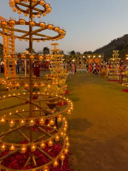 The warm glow of hundreds of diyas on traditional brass stands, lighting up the lawn for a beautiful Garba night.