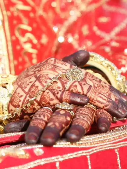 A bride's hands are incomplete without a lovely dark henna stain. This photo captures the beauty of the mature stain against her red bridal attire.