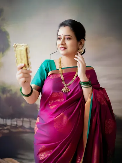 A graceful and traditional portrait. The mom-to-be, dressed in a beautiful silk saree, looks in a mirror, capturing a moment of quiet reflection.