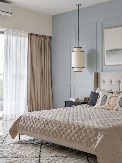 A serene bedroom from the Neutral Chic home, with a dusty blue paneled wall and a classic tufted headboard. The design is calm, sophisticated, and timeless.