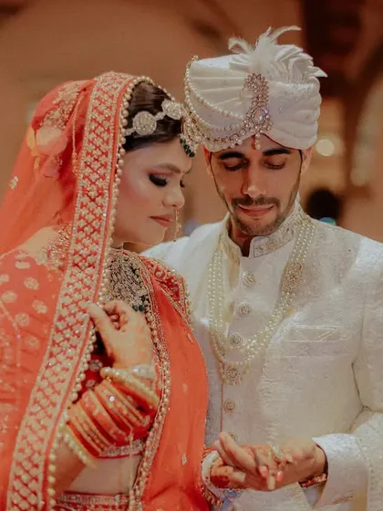 An intimate moment between the bride and groom during a wedding ritual. Their focused expressions and gentle interaction create a beautiful, serene image.