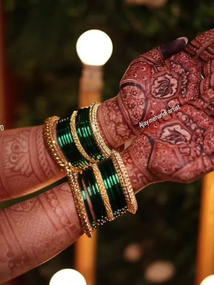 A close-up of the beautiful dark stain, complemented by traditional green bangles. The intricate details of the design are still sharp and clear.