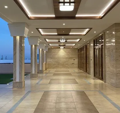 The expansive semi-outdoor veranda at dusk. We designed this space as a seamless transition between the interior and the landscape, with elegant columns and sophisticated ceiling lighting.
