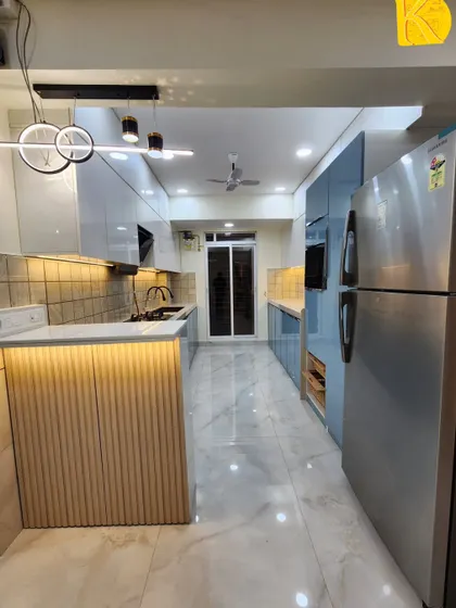 A wide-angle view of the entire parallel kitchen, including the breakfast bar and the passage leading to the utility area.
