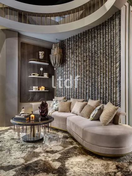 A refined blend of luxury and comfort. This interior features a plush curved sofa set against a textured feature wall that adds depth and dimension. Rich materials, layered lighting, and sculptural decor create a sophisticated yet inviting ambiance.