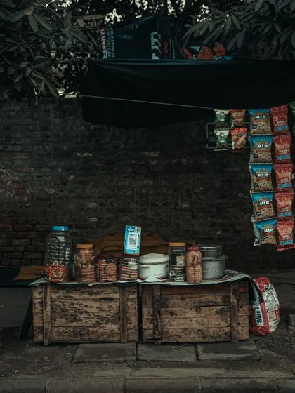 A rustic wooden stall with jars of snacks. This image is all about texture and nostalgia, capturing the simple, old-school charm of a neighborhood shop.