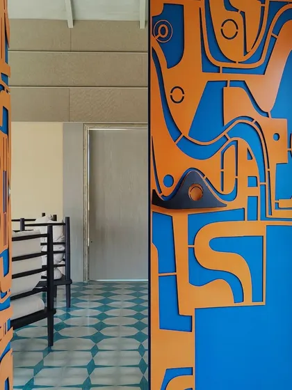 A door is never just a door for us. This custom-fabricated metal door, with its bold orange and blue abstract design, acts as a powerful architectural statement, setting the tone for the entire home before you even step inside.