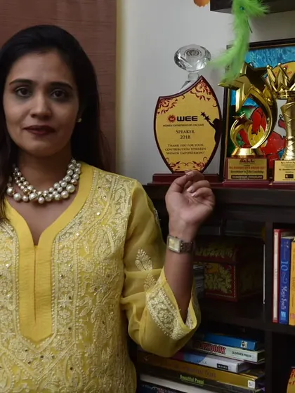 Standing proudly with my awards. This shelf holds memories of my journey, from a WEE speaker award to many others, each marking a special milestone.