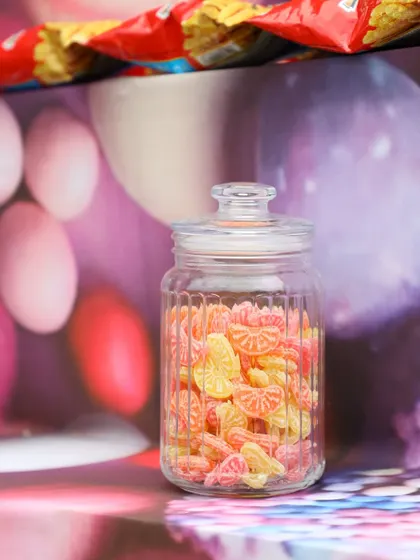 A jar of colorful orange-slice candies, part of the fun and detailed setup of the 90s nostalgia bar.